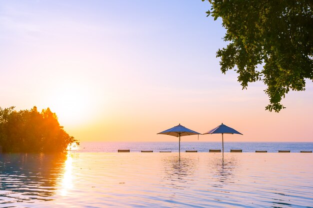 Hermoso paisaje de piscina al aire libre con sombrilla y tumbona en el hotel resort para relajarse tra