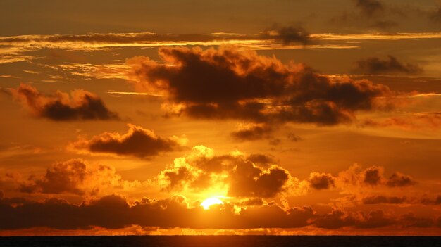 Hermoso paisaje en la playa con puesta de sol y nubes