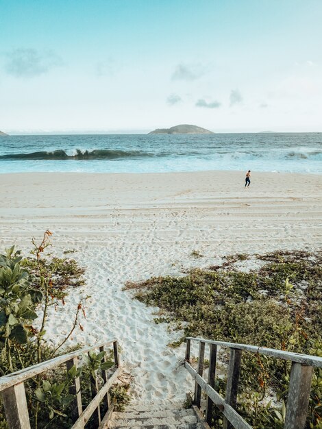 Hermoso paisaje de la playa durante la puesta de sol con una persona haciendo ejercicio