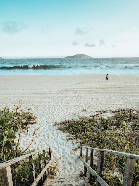 Hermoso paisaje de la playa durante la puesta de sol con una persona haciendo ejercicio