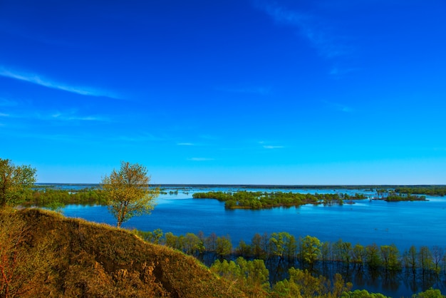 Hermoso paisaje primaveral. Increíble vista de las inundaciones desde la colina. Europa. Ucrania. Impresionante cielo azul con nubes blancas