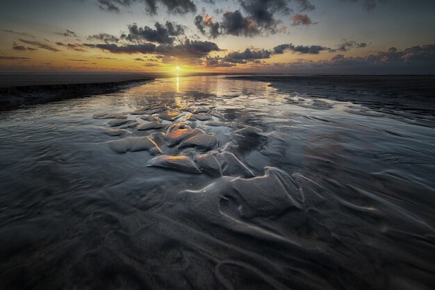 Hermoso paisaje de la puesta del sol reflejada en una marisma bajo el cielo nublado