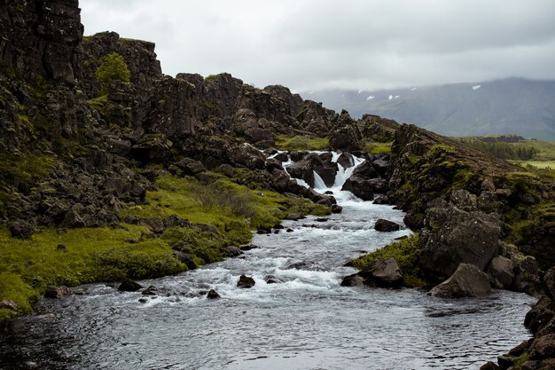 Hermoso paisaje de un río que fluye cerca de formaciones rocosas en Islandia