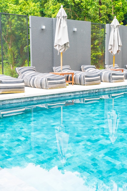 Foto gratuita hermoso paraguas de lujo y una silla alrededor de la piscina al aire libre