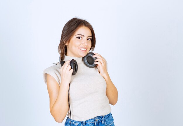 Hermoso de pie y posando con auriculares sobre fondo blanco.