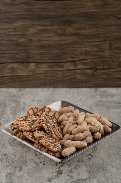 Un hermoso plato con galletas de avena y nueces aislado sobre un fondo de piedra.