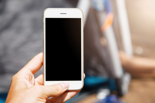 Hermoso primer plano del moderno smartphone blanco. Mujer sosteniendo su gadget apagado actualizado con la mano y presionando el botón de inicio.