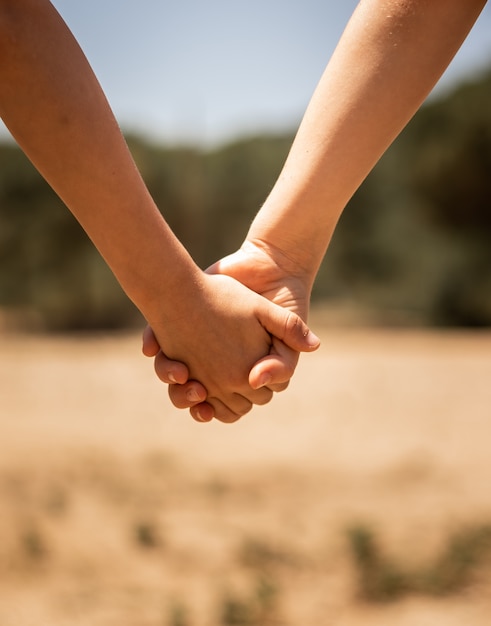 Hermoso primer plano de una pareja cogidos de la mano sobre un fondo borroso de un campo