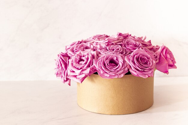 Hermoso ramo floral con rosas rosadas en una caja sobre un fondo rosa