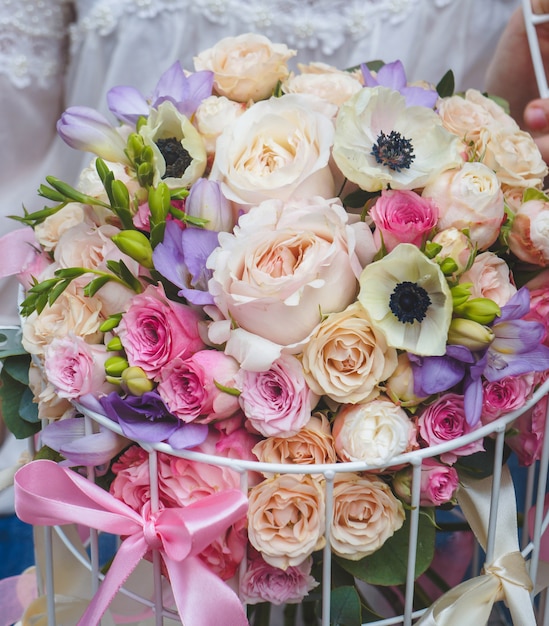 Un hermoso ramo de flores de color pastel en un contenedor de jaula