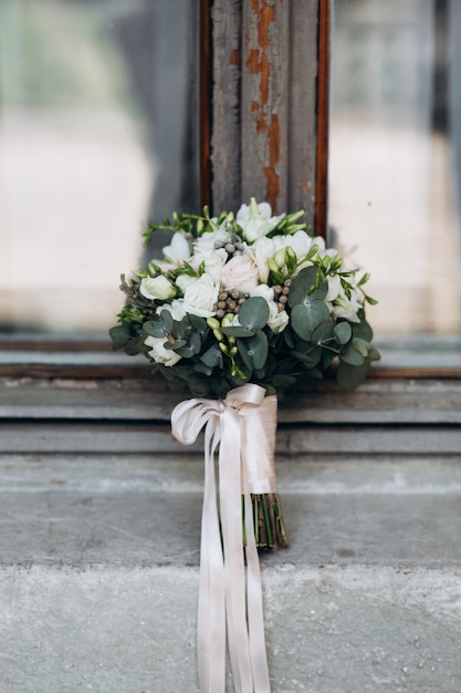 Foto gratuita hermoso ramo de novia con un tipo de satén se encuentra en la celda de la ventana