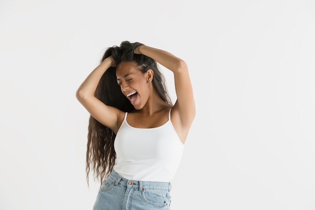 Hermoso retrato femenino de medio cuerpo aislado en la pared blanca. Joven mujer afroamericana emocional con cabello largo. Expresión facial, concepto de emociones humanas. Se siente locamente feliz, saltando.