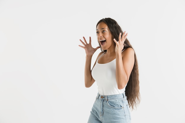 Hermoso retrato femenino de medio cuerpo aislado sobre fondo blanco de estudio. Joven mujer afroamericana emocional con cabello largo. Expresión facial, concepto de emociones humanas. Asombrado, emocionado.