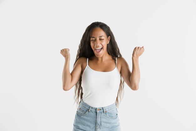 Hermoso retrato femenino de medio cuerpo aislado sobre fondo blanco de estudio. Joven mujer afroamericana emocional con cabello largo. Expresión facial, concepto de emociones humanas. Celebrando y sonriendo.