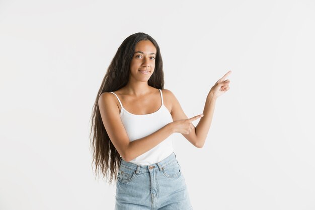 Hermoso retrato femenino de medio cuerpo aislado sobre fondo blanco de estudio. Joven mujer afroamericana emocional con cabello largo. Expresión facial, concepto de emociones humanas. Mostrando una barra espaciadora vacía.