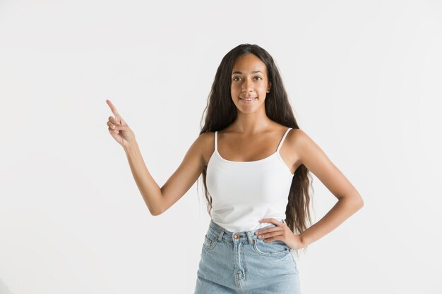 Hermoso retrato femenino de medio cuerpo aislado sobre fondo blanco de estudio. Joven mujer afroamericana emocional con cabello largo. Expresión facial, concepto de emociones humanas. Mostrando una barra espaciadora vacía.