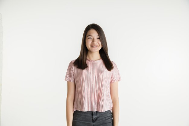 Hermoso retrato femenino de medio cuerpo aislado sobre fondo blanco de estudio. Mujer joven emocional en ropa casual. Las emociones humanas, el concepto de expresión facial. Sonriendo, parece confiado.