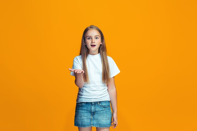 Hermoso retrato femenino de medio cuerpo sobre fondo de color naranja de estudio. La joven adolescente emocional