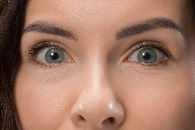 Hermoso retrato frontal de media cara femenina aislado sobre fondo rosa de estudio. Joven mujer sorprendida emocional de pie con la boca abierta. Las emociones humanas, el concepto de expresión facial.