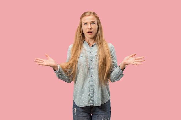 Hermoso retrato frontal de medio cuerpo femenino aislado sobre fondo rosa de estudio. joven mujer sorprendida emocional de pie con la boca abierta. las emociones humanas, el concepto de expresión facial.