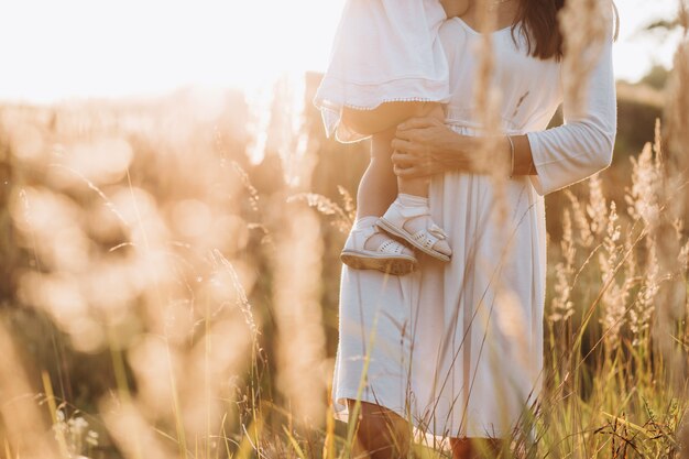 Hermoso retrato de una madre encantadora y una pequeña y encantadora hija caminando por el campo