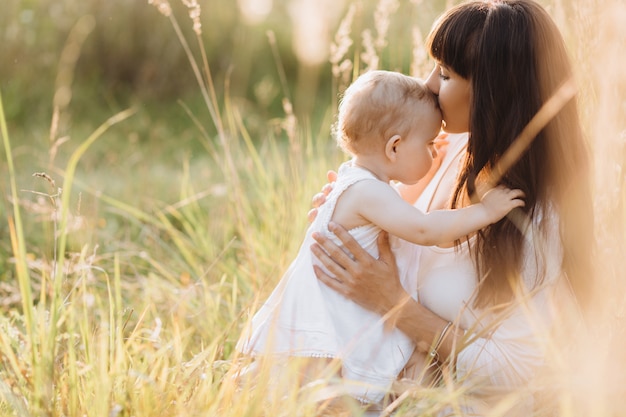 Hermoso retrato de una madre encantadora y una pequeña y encantadora hija caminando por el campo