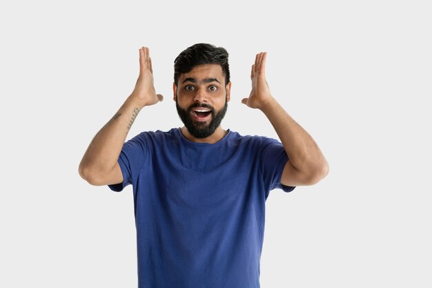 Hermoso retrato masculino aislado. Joven hindú emocional en camisa azul. Asombrado, conmocionado, loco de felicidad.