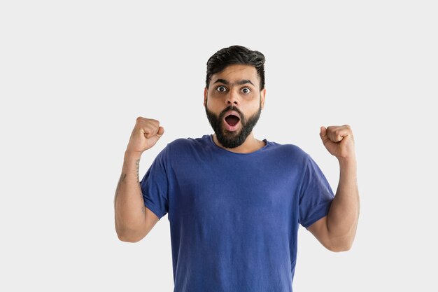 Hermoso retrato masculino de medio cuerpo aislado en la pared blanca. Joven hindú emocional en camisa azul. Expresión facial, emociones humanas, concepto publicitario. Asombrado, conmocionado, loco de felicidad.