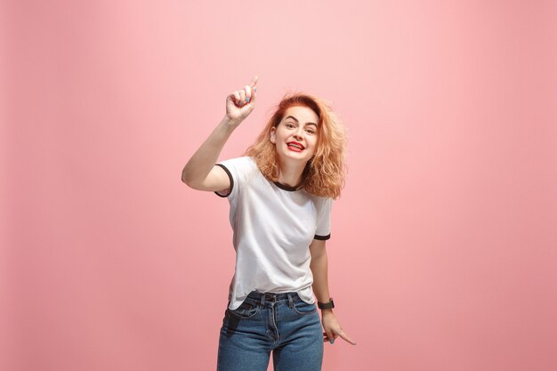 Hermoso retrato de medio cuerpo femenino aislado en la pared de color rosa. La joven mujer sorprendida emocional