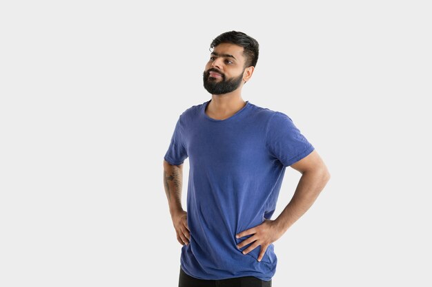 Hermoso retrato de medio cuerpo masculino aislado sobre fondo blanco de estudio. Joven hindú emocional en camisa azul. Expresión facial, emociones humanas, concepto publicitario. De pie y sonriendo.