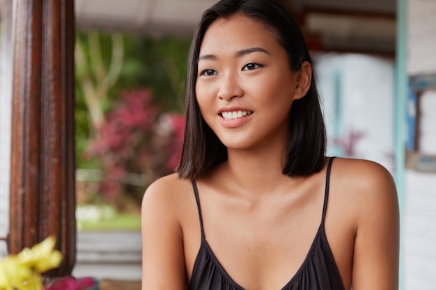 Hermoso retrato de mujer china con peinado bobbed, posa en una acogedora habitación