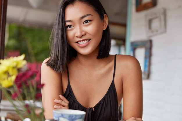 Hermoso retrato de mujer china con peinado bobbed, posa en una acogedora habitación