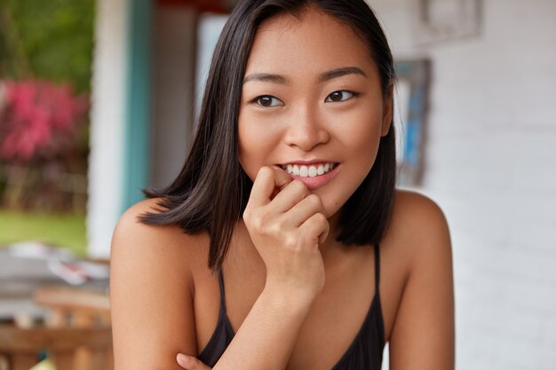 Hermoso retrato de mujer china con peinado bobbed, posa en una acogedora habitación