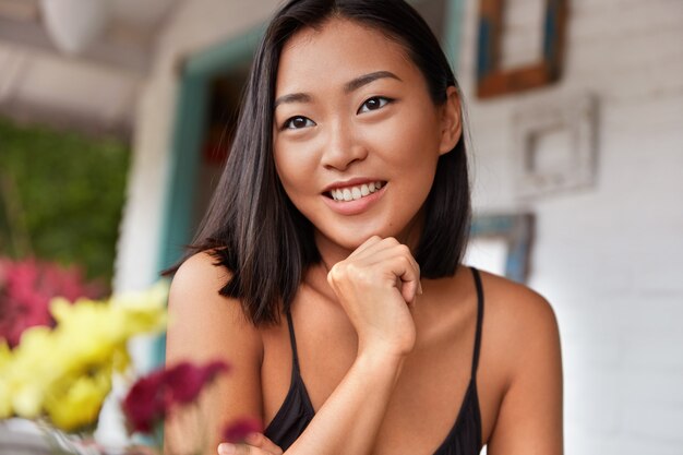 Hermoso retrato de mujer china con peinado bobbed, posa en una acogedora habitación