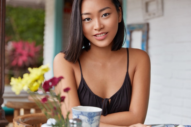 Hermoso retrato de mujer china con peinado bobbed, posa en una acogedora habitación