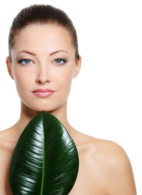 Foto gratuita hermoso rostro de mujer fresca con grandes hojas verdes, aisladas