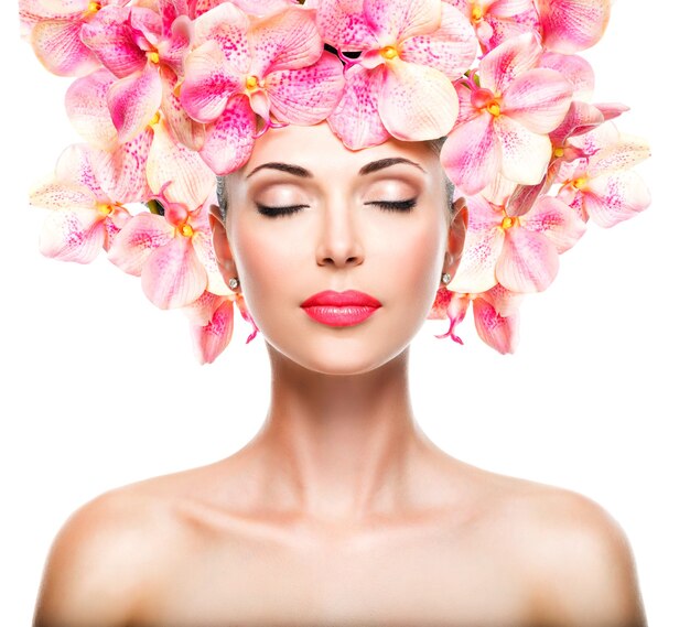 Hermoso rostro relajado de una joven con piel clara y orquídeas rosadas. Concepto de tratamiento de belleza