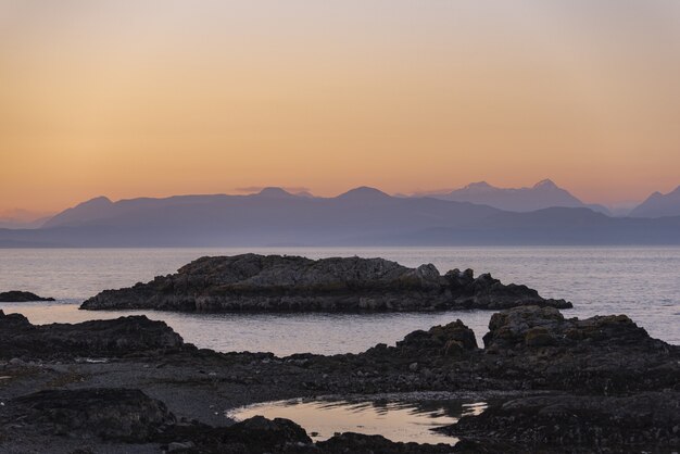 Hermoso tiro de acantilados rocosos cerca del mar bajo un cielo rosado