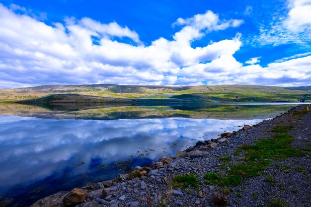 Hermoso tiro de agua cerca de la costa rocosa y la montaña en la distancia con nubes en el cielo