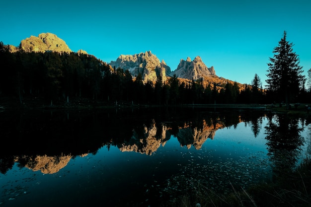 Hermoso tiro de agua que refleja los árboles y las montañas con cielo azul