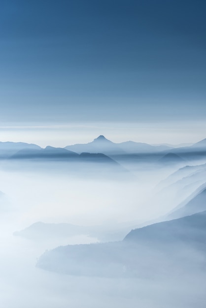 Hermoso tiro de altas colinas blancas y montañas cubiertas de niebla