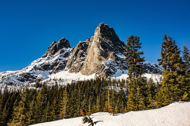 Hermoso tiro de altas montañas rocosas y colinas cubiertas de nieve sobrante en primavera