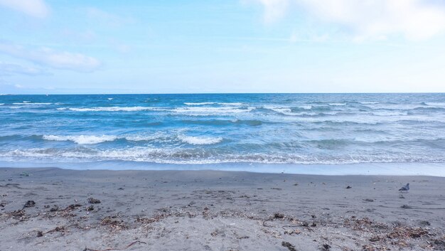 Hermoso tiro ancho de una playa de arena con increíbles olas del mar y cielo azul