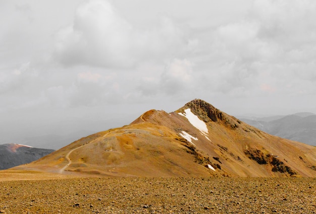 Hermoso tiro de un campo con una montaña en la distancia bajo un cielo nublado