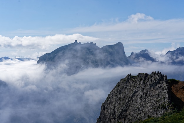 Hermoso tiro desde la cima de la montaña sobre las nubes con una montaña en la distancia