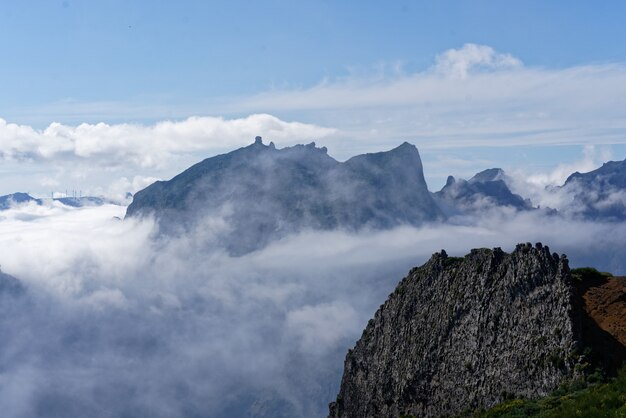 Hermoso tiro desde la cima de la montaña sobre las nubes con una montaña en la distancia