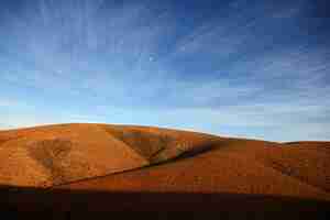 Foto gratuita hermoso tiro de colinas desiertas bajo un cielo azul durante el día