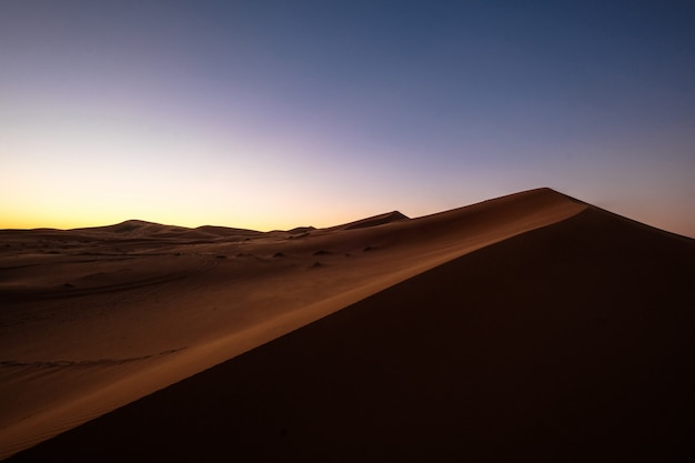 Hermoso tiro de dunas de arena bajo un cielo morado y azul