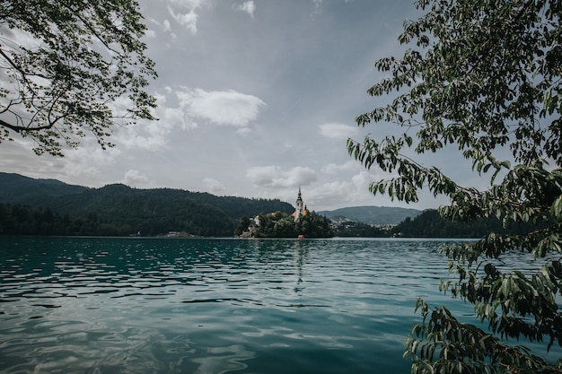 Hermoso tiro del lago sangrado con un edificio rodeado de árboles en la distancia