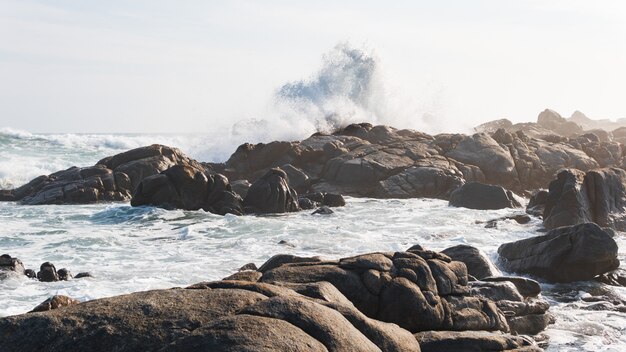 Hermoso tiro de las olas del océano tormentoso que alcanza las piedras en la orilla